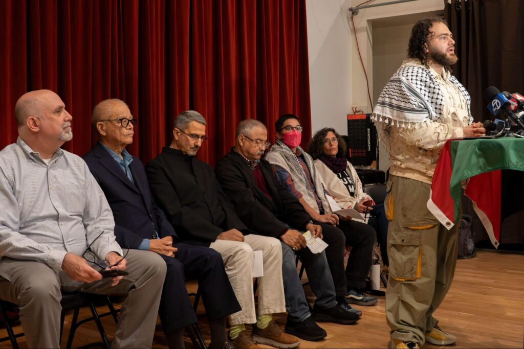 Abdulrahim Harara of Jerusalem Coffee House speaks to the press. Speakers lined up behind him include Walter Riley and Dr. Hatem Bazian.